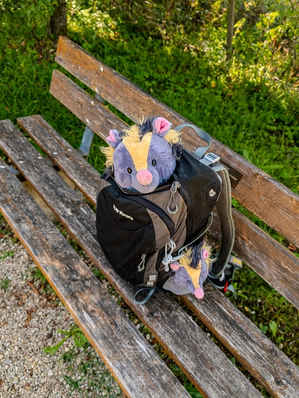Gruppenfoto auf der Mohnstriezel-Bank: Klein Viki und mini Christopher posieren im Rucksack, während Baby Viki nach Süßigkeiten taucht
